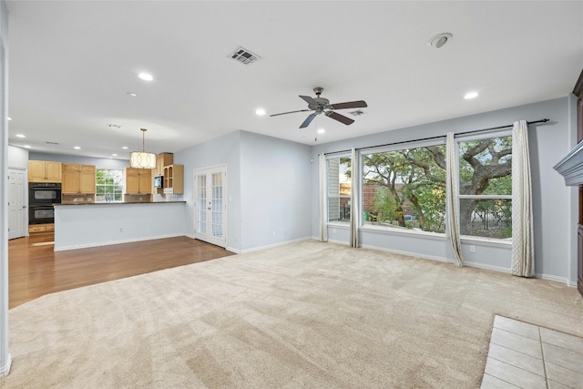 unfurnished living room featuring ceiling fan and light carpet