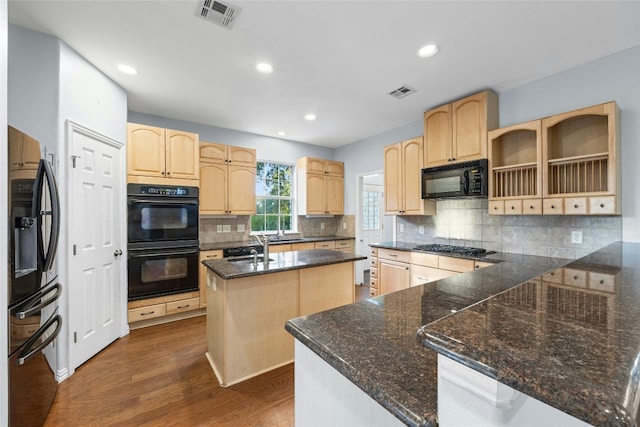 kitchen featuring an island with sink, black appliances, decorative backsplash, and dark wood-type flooring