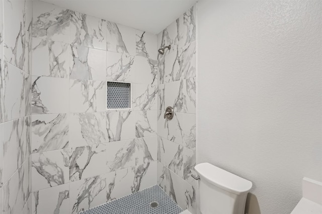 bathroom featuring toilet and a tile shower