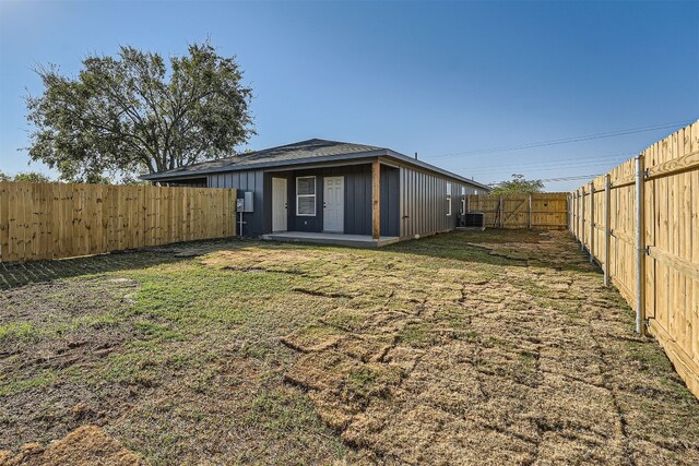 rear view of property with cooling unit and a lawn