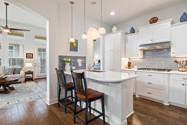 kitchen with dark wood-type flooring, white cabinets, stainless steel gas cooktop, and sink