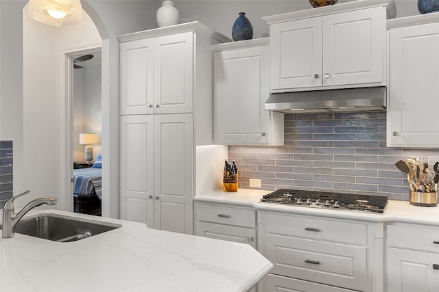 kitchen featuring decorative backsplash, sink, hanging light fixtures, white cabinetry, and stainless steel gas stovetop