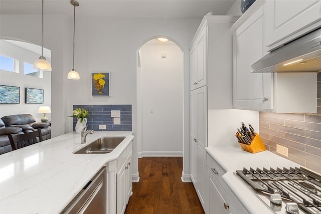 kitchen with tasteful backsplash, decorative light fixtures, sink, and white cabinetry