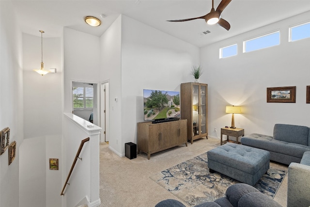 living room featuring light carpet, ceiling fan, and a towering ceiling