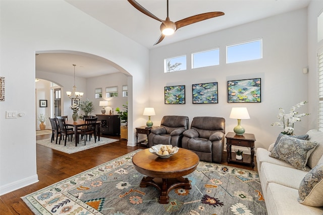 living room with ceiling fan with notable chandelier and dark hardwood / wood-style floors