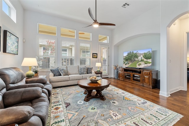 living room with ceiling fan, a towering ceiling, and dark hardwood / wood-style flooring