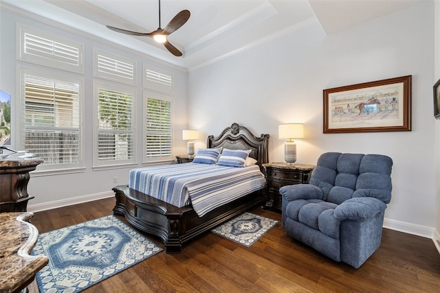 bedroom with dark wood-type flooring, ornamental molding, a raised ceiling, and ceiling fan