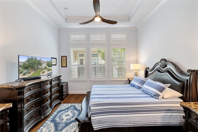 bedroom with dark wood-type flooring, a tray ceiling, crown molding, and ceiling fan