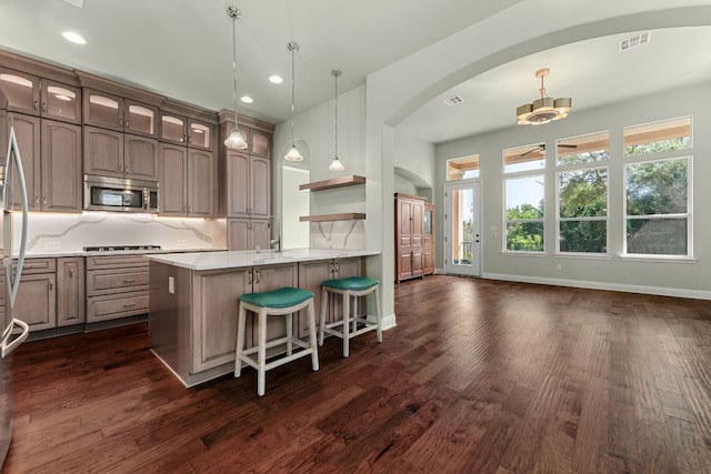 214 Darwins Way, Lakeway, TX 78734 - kitchen with stainless steel microwave, arched walkways, gas cooktop, light countertops, and dark wood-type flooring