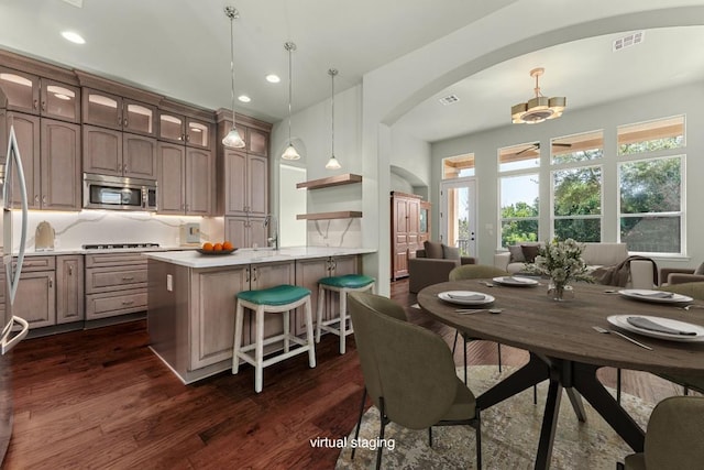 214 Darwins Way, Lakeway, TX 78734 - kitchen featuring stainless steel microwave, arched walkways, gas stovetop, dark wood-type flooring, and a peninsula