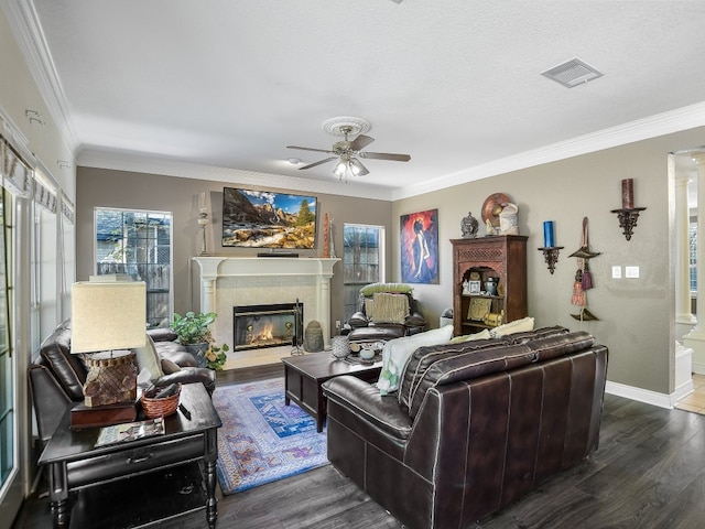 living room featuring ceiling fan, dark hardwood / wood-style floors, a fireplace, ornamental molding, and a textured ceiling