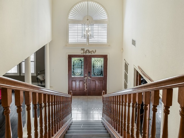 entryway featuring a high ceiling, tile patterned flooring, and a chandelier