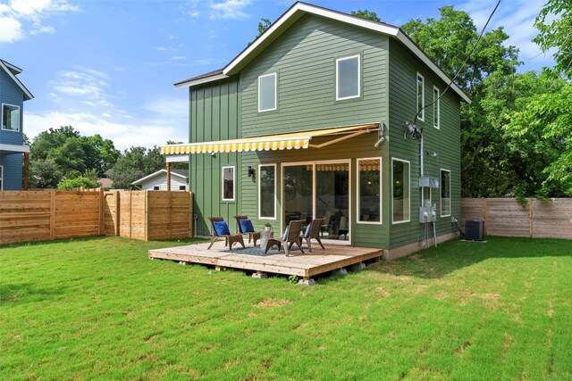 rear view of house with cooling unit, a wooden deck, and a lawn