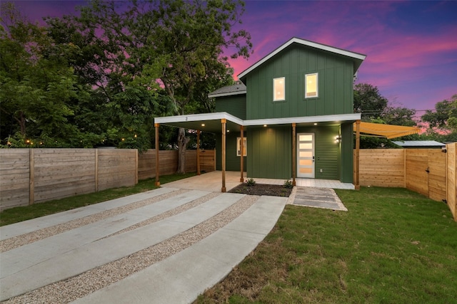 back house at dusk featuring a yard and a carport