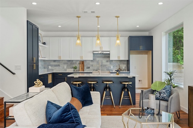 kitchen with light wood-type flooring, hanging light fixtures, decorative backsplash, and white cabinetry