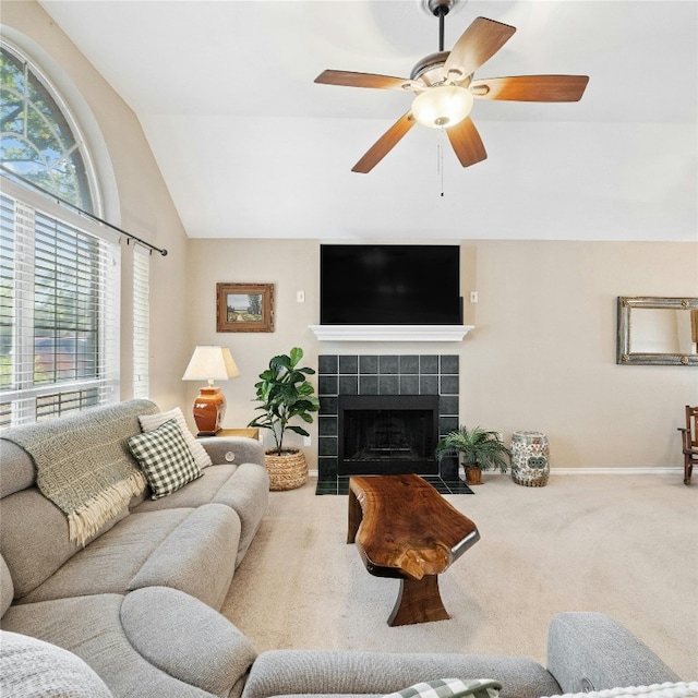 living room featuring a tiled fireplace, plenty of natural light, vaulted ceiling, and carpet