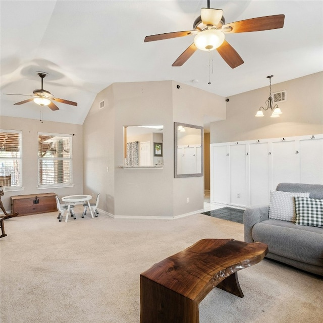 living room with ceiling fan with notable chandelier, light colored carpet, and vaulted ceiling