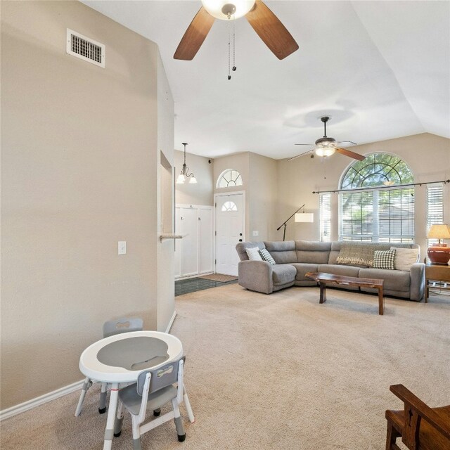 living room with ceiling fan with notable chandelier, lofted ceiling, and carpet