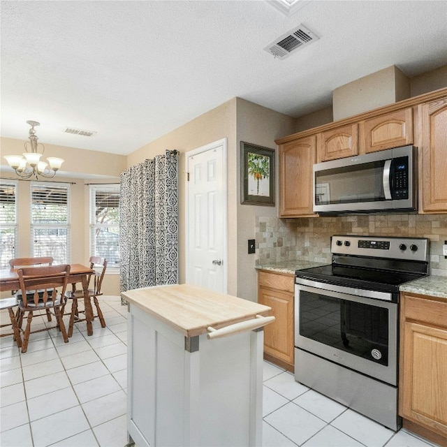 kitchen featuring a chandelier, backsplash, appliances with stainless steel finishes, light tile patterned floors, and a textured ceiling