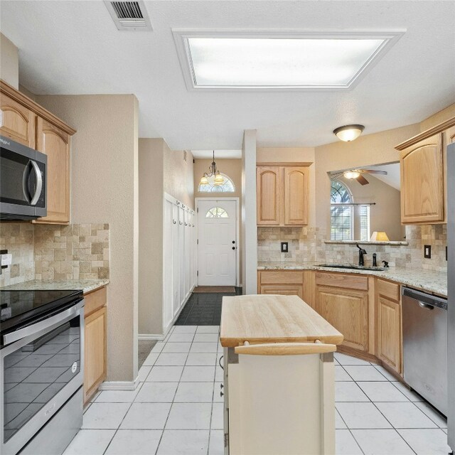 kitchen featuring light brown cabinetry, appliances with stainless steel finishes, backsplash, and sink