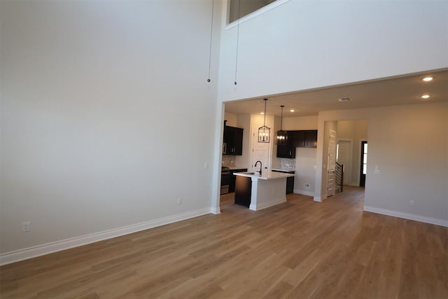 unfurnished living room with recessed lighting, light wood-type flooring, baseboards, and a sink