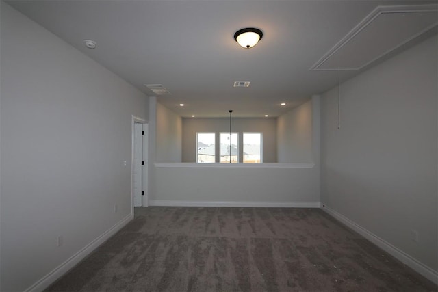 carpeted spare room featuring visible vents, attic access, and baseboards