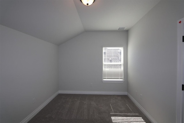 unfurnished room with visible vents, dark carpet, baseboards, and vaulted ceiling