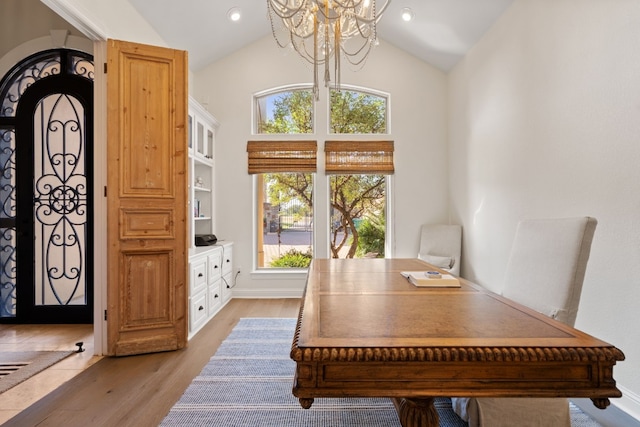 office area featuring light hardwood / wood-style floors, lofted ceiling, and a notable chandelier