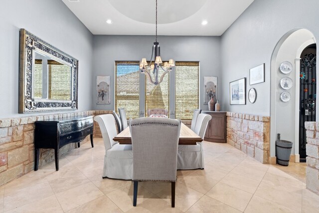 tiled dining area with a raised ceiling and an inviting chandelier