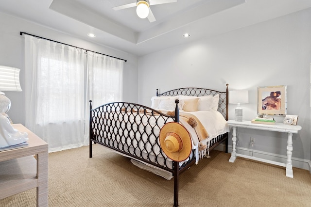 bedroom featuring ceiling fan, a raised ceiling, and light colored carpet