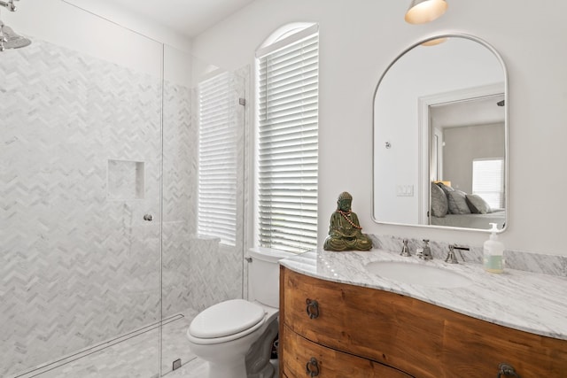 bathroom with vanity, toilet, and tiled shower