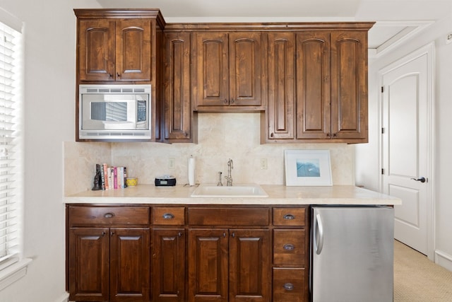 kitchen featuring backsplash, stainless steel microwave, sink, and fridge