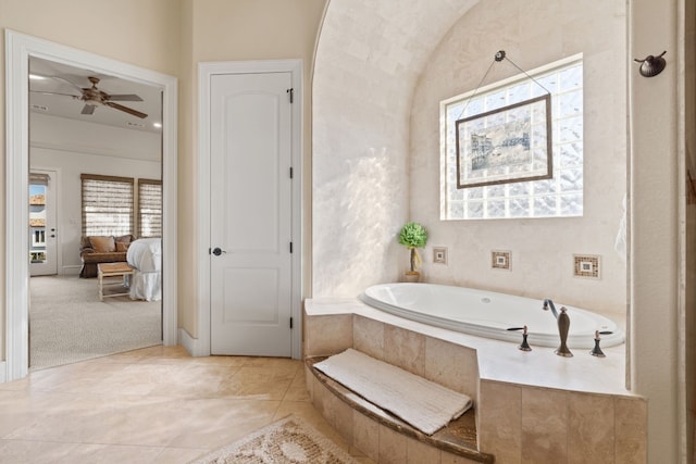 bathroom with a relaxing tiled tub and ceiling fan