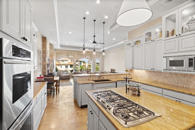 kitchen with stainless steel appliances, ceiling fan, a center island, white cabinetry, and hanging light fixtures