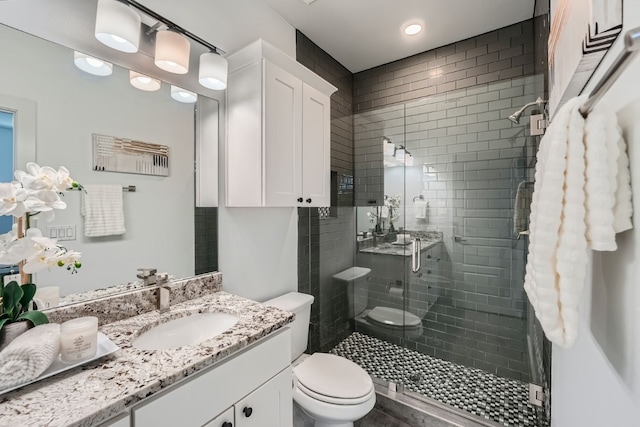 bathroom featuring vanity, a shower with door, and toilet