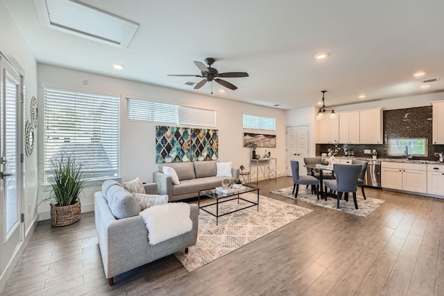 living room featuring wood-type flooring, sink, and ceiling fan