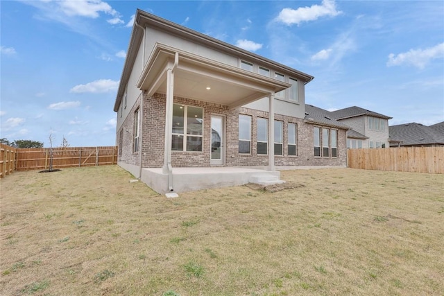 back of property with a yard, a patio, brick siding, and a fenced backyard