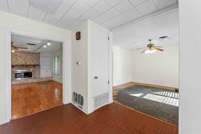 unfurnished living room featuring a stone fireplace, ceiling fan, and dark wood-type flooring