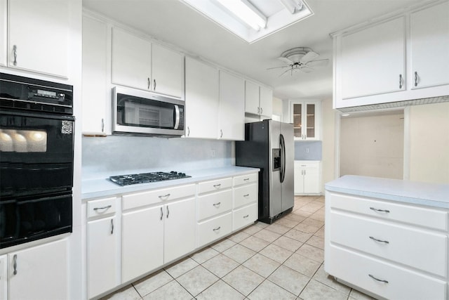 kitchen featuring decorative backsplash, appliances with stainless steel finishes, ceiling fan, white cabinetry, and light tile patterned flooring