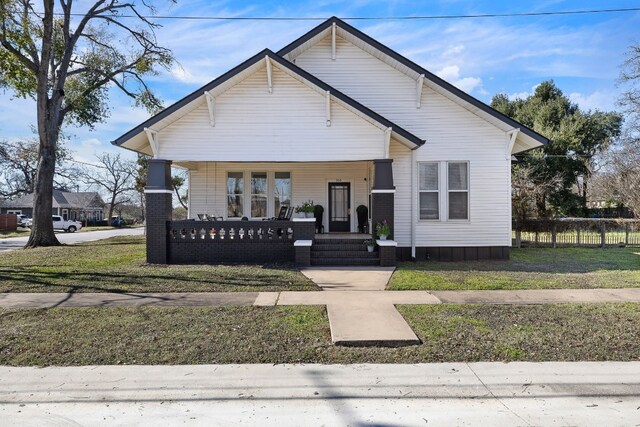 bungalow-style home with covered porch and a front yard