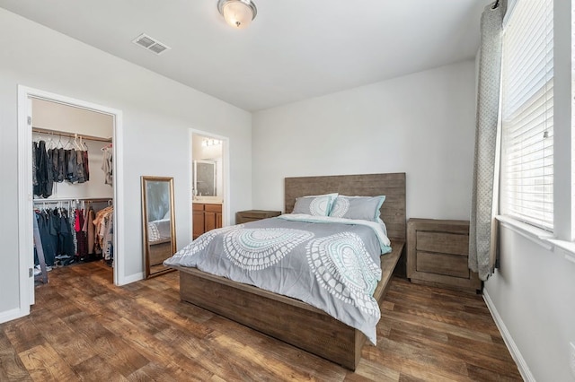 bedroom featuring a spacious closet, a closet, connected bathroom, and dark hardwood / wood-style floors