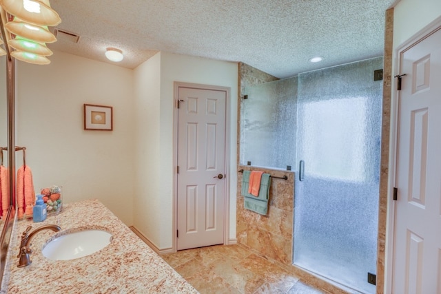 bathroom with vanity, a textured ceiling, and walk in shower