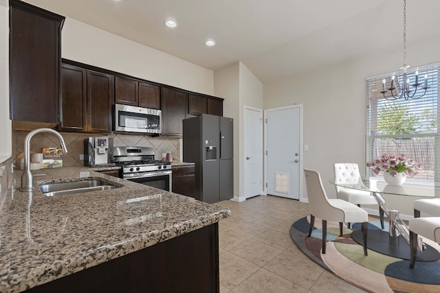 kitchen with stainless steel appliances, backsplash, dark brown cabinets, stone countertops, and sink