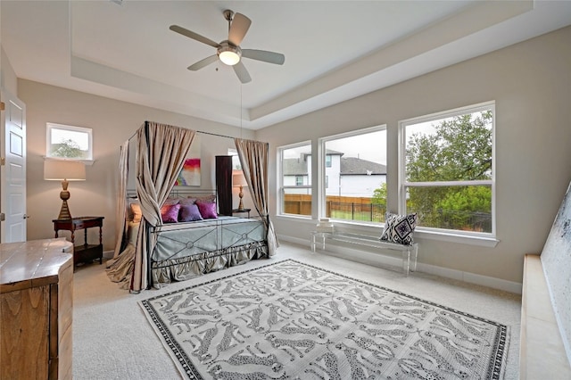 carpeted bedroom with ceiling fan and a raised ceiling