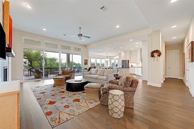 living room featuring a fireplace, wood-type flooring, and ceiling fan