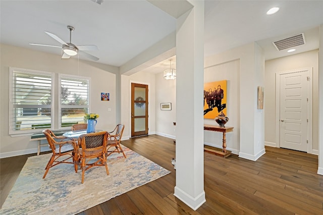 dining area with ceiling fan with notable chandelier and dark hardwood / wood-style floors