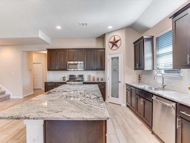 kitchen featuring backsplash, appliances with stainless steel finishes, sink, and a center island