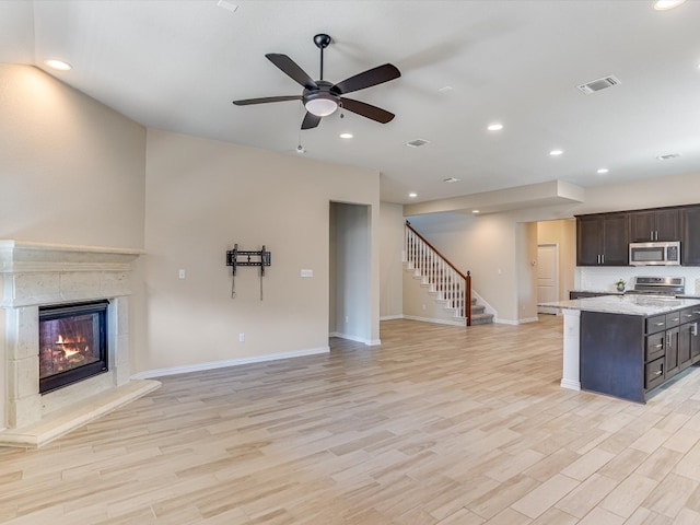 unfurnished living room featuring ceiling fan, light hardwood / wood-style floors, and a tile fireplace