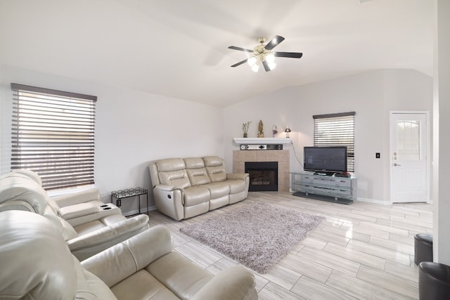 living room with lofted ceiling, a tile fireplace, light wood-type flooring, and ceiling fan