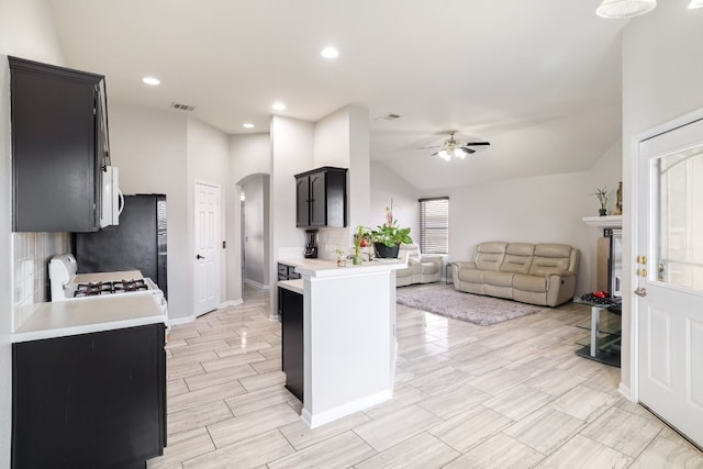 kitchen featuring lofted ceiling, ceiling fan, decorative backsplash, white appliances, and kitchen peninsula